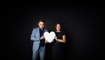 man and woman in business attire holding a love heart between them
